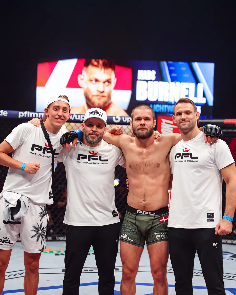 Mads Burnell i buret efter sin kamp i Professional Fighters League, sammen med medstifter Nicolai Wie og resten af hjørneteamet fra Burnell MMA & BJJ